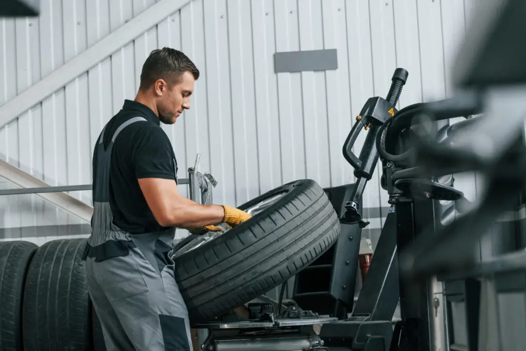 walking and holding tyre. man in uniform is working in the auto service
