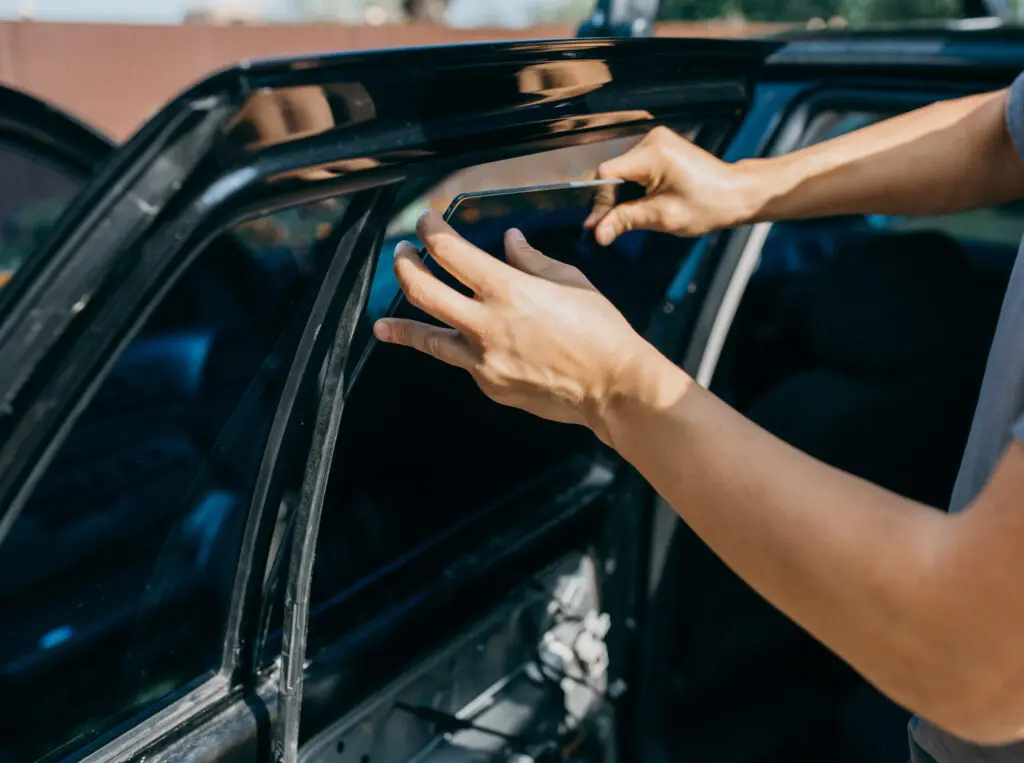 Mann wechselt im Freien die Seitenscheibe eines Fahrzeugs