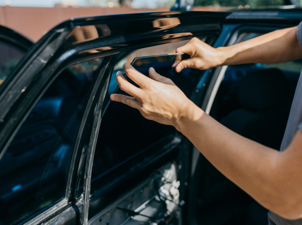 Mann wechselt im Freien die Seitenscheibe eines Fahrzeugs